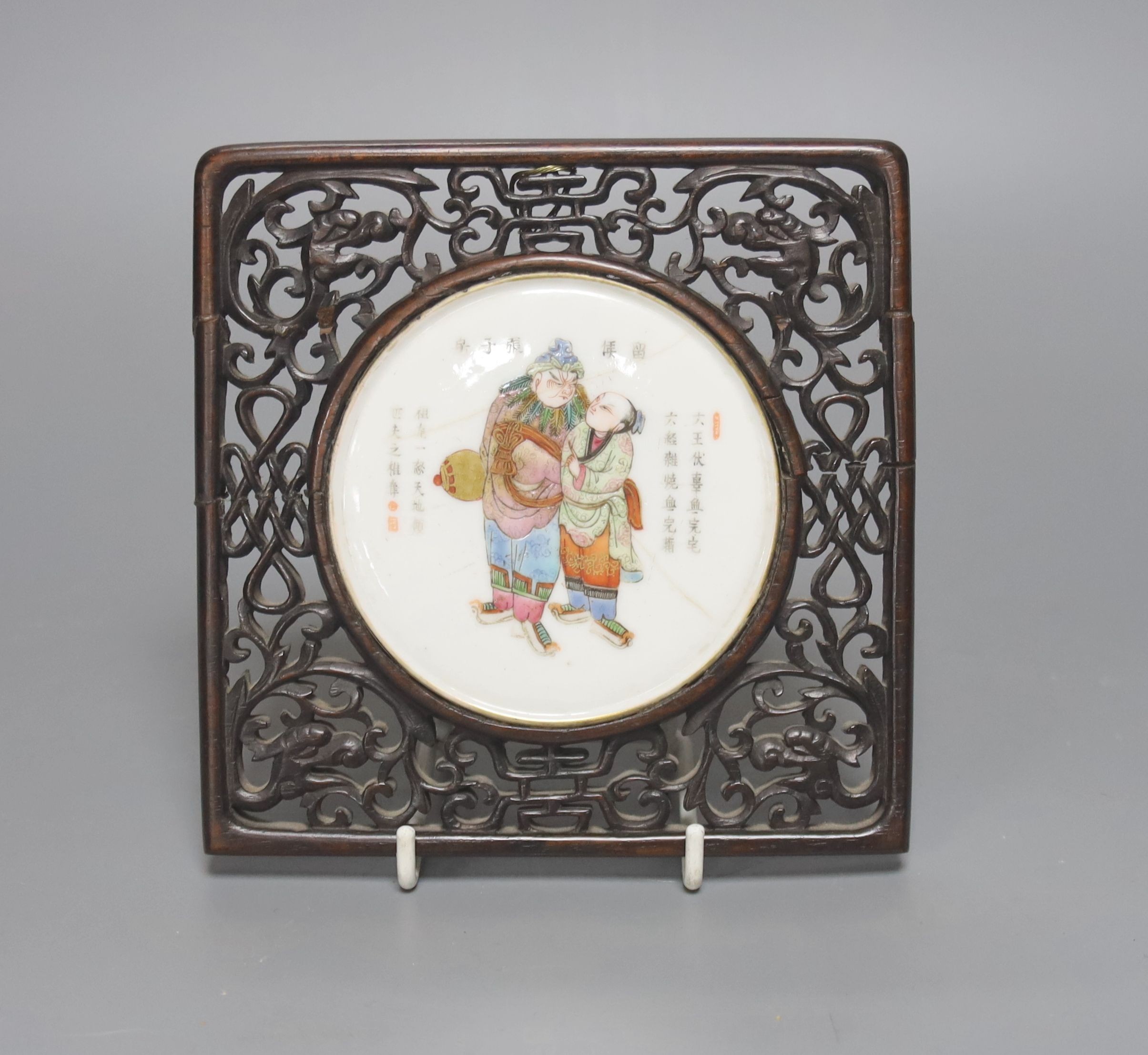 A 19th century Chinese famille rose circular plaque or cover, inset into a wood surround, cracks 15cm sq